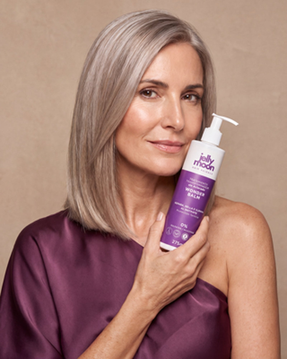 Mujer de melena plateada con un bote de WonderBalm